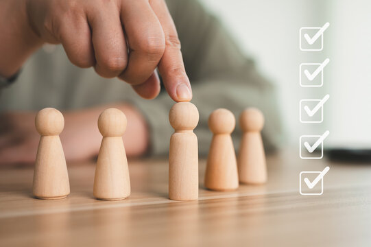 Human resource management and recruitment concept. hand choosing wooden figure from row for candidate selection, performance appraisal.
