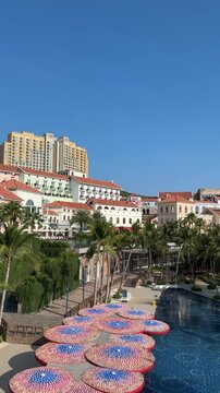 4k footage showing a clock tower with European-style buildings with colorful roofs and palm trees. The bright sunny day with lush green plants across the resort town.