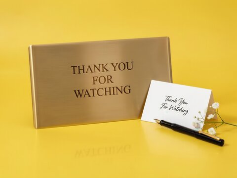 A sleek golden plaque and card with Thank You For Watching text sits on a bright yellow surface. Ideal for video outro and creator appreciation concepts.