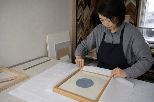 Japanese custom framer wrapping a finished picture frame