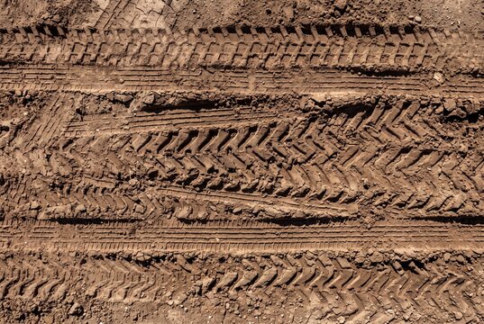 Tractor tire tracks on dry brown dirt ground, top view
