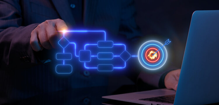 Businessman using laptop computer while finger touching glowing workflow process flowchart leading to target bullseye icon. Business process optimization and strategic execution target concept.