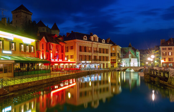 Historic buildings, stone bridges and canal reflections in central Annecy, France, during blue hour.