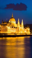 Naklejka premium Golden domed cathedral at sunset with reflections on water.