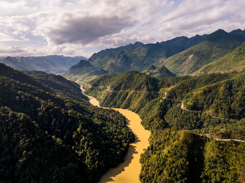 Aerial view of the Ha Giang Loop winding through lush green mountains and the Nho Que River in Dong Van, Tuyen Quang, Vietnam.