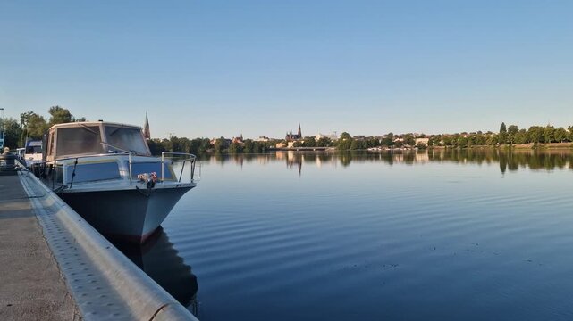 Moored cabin boat with calm lake and Schwerin skyline in Germany