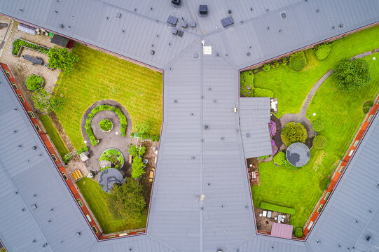 Aerial view of a modern building complex with grey rooftops, green courtyards, manicured lawns, and paved pathways in Molndal, Vastra Gotaland County, Sweden.