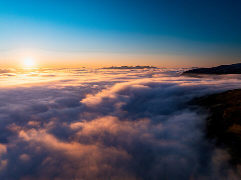 Aerial view of a dramatic cloud inversion at sunset over the rugged mountains of Tromso, Troms, Norway.