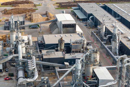 Aerial view of a modern and advanced wood processing facility with industrial pipes, silos, and conveyor belts in Poland.