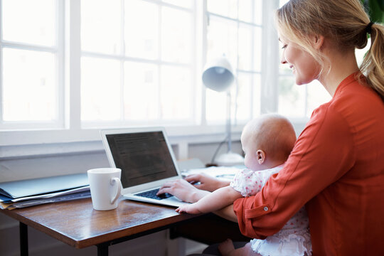 Mom, baby and laptop for remote work with multitasking, email feedback and childcare in home. Happy woman, infant child and computer with typing, review or blog with parenting, WFH and productivity