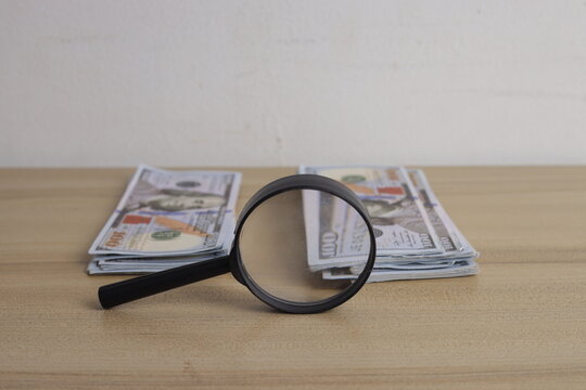 Closeup of Magnifying Glass Placed Alongside Dollar Banknotes
