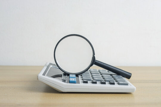 Magnifying Glass Resting on Top of Office Calculator
