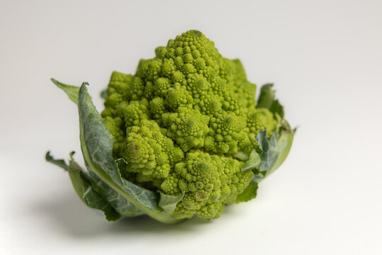 Fresh Romanesco broccoli head with green leaves isolated on white background