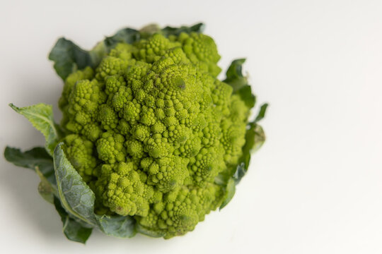 Fresh Romanesco broccoli head with green leaves isolated on white background