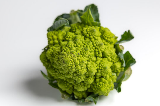 Fresh Romanesco broccoli head with green leaves isolated on white background