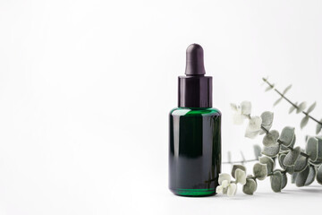 Green essential oil dropper bottle with eucalyptus leaves © thanksforbuying