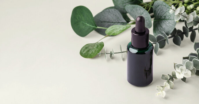Green essential oil dropper bottle with green leaves decoration, natural skincare, wellness, and aromatherapy