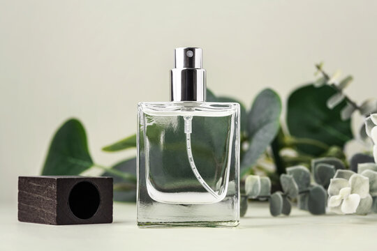 Perfume or glass cosmetic spray bottle with wooden cap mockup with green leaves decoration on green background