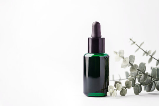 Green essential oil dropper bottle with eucalyptus leaves