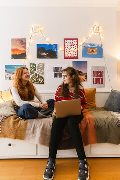 Two teenage girls talking and laughing during a relaxed conversation at home