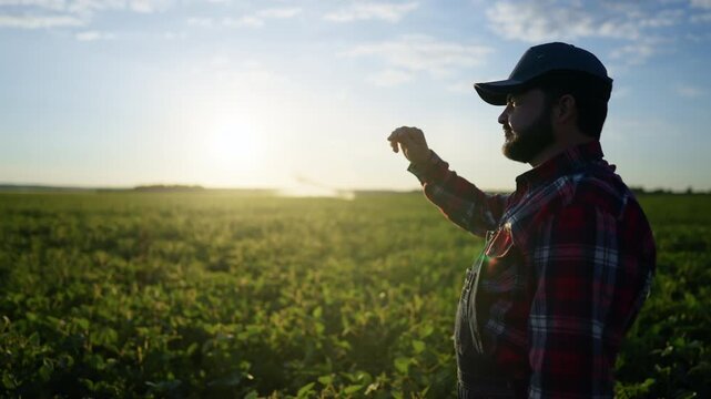 Professional agronomist controlling works in farmland, modern irrigation system. Farmer standing in beautiful field, sustainable agriculture. Minimizing use of synthetic fertilizers and pesticides