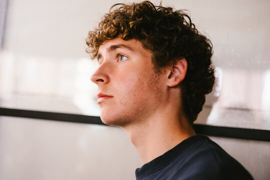 Thoughtful young man with curly hair looking ahead