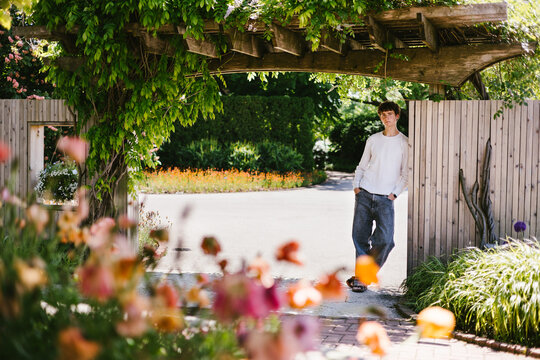 Young man relaxes under a vine covered garden arch
