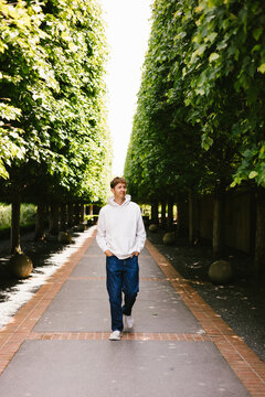 Young man walking on a tree lined path