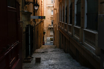 Fototapeta premium Narrow street with parked cars leading to the sea in valletta, malta