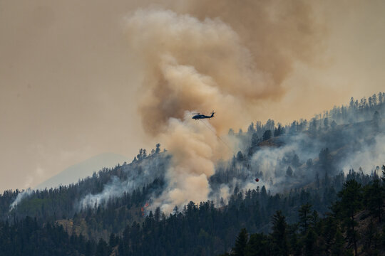 Firefighting helicopter battles a smoky mountain wildfire