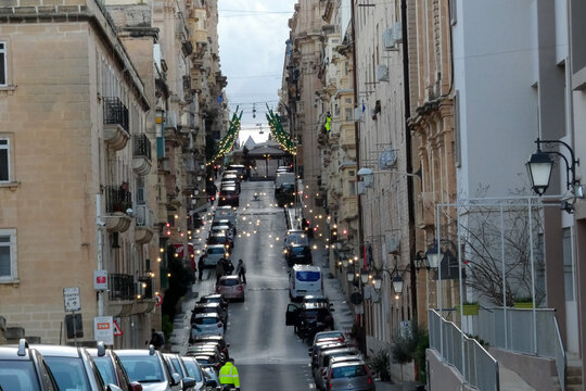 Narrow street with parked cars leading to the sea in valletta, malta