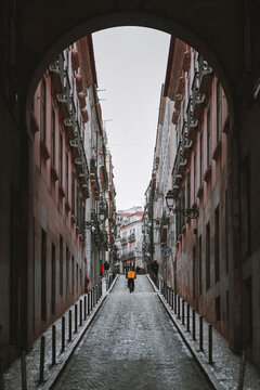 Food delivery courier cycles up a narrow Lisbon alley
