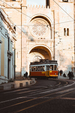 A classic yellow tram turns a corner in Lisbon