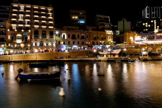 Spinola bay, st. Julian's, malta at night showing illuminated buildings and boats