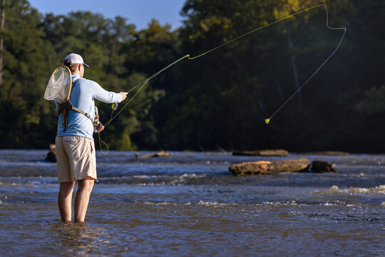 Fly fisherman casting his line into a flowing river