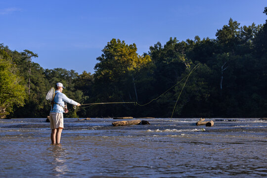 Man fly fishing while standing in a shallow river