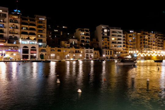 Spinola bay, st. Julian's, malta at night showing illuminated buildings and boats