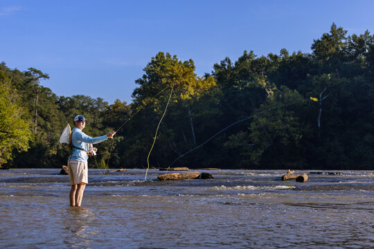 Man fly fishing and casting a line in a river