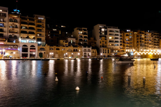 Spinola bay, st. Julian's, malta at night showing illuminated buildings and boats