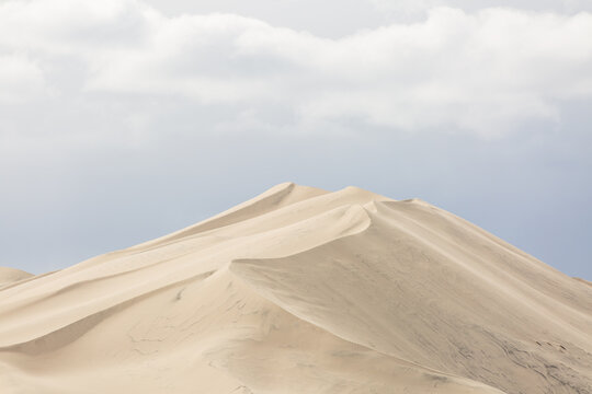 Minimalist sand dune curves against a soft sky
