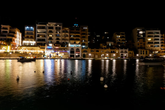 Spinola bay, st. Julian's, malta at night showing illuminated buildings and boats