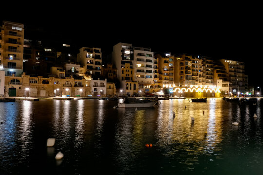 Spinola bay, st. Julian's, malta at night showing illuminated buildings and boats