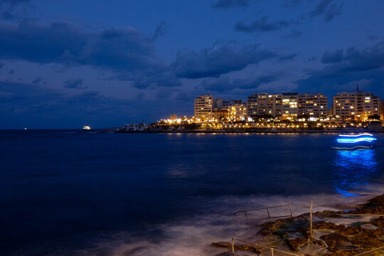 Spinola bay, st. Julian's, malta at night showing illuminated buildings and boats
