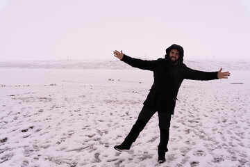 Happy Man in Black Parka with Arms Open Embracing Winter Nature © ANGEL LARA FOTO