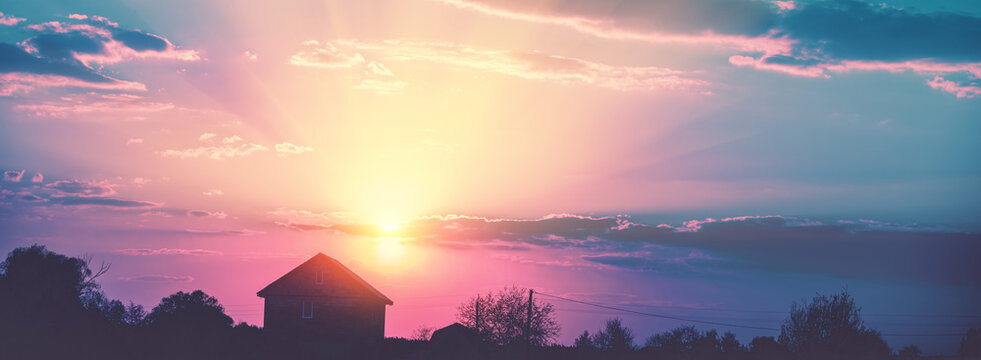 Rural landscape with beautiful gradient sky at sunset. Silhouette of houses against the sky