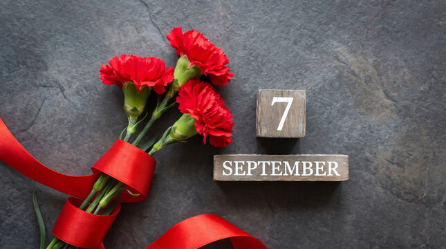 Labor day celebration with red carnations and number seven on slate background