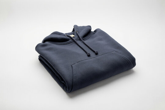 Folded dark gray hoodie with drawstrings on white background, minimalist apparel product photo for online store, casual unbranded sweatshirt