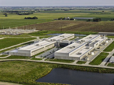 Aerial view of a large data center facility surrounded by green fields and farmland in DeKalb, Illinois, United States.