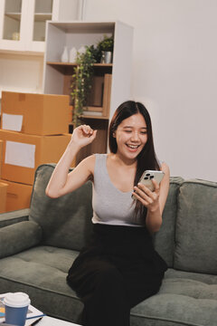 Startup SME small business entrepreneur of freelance Asian woman wearing apron using laptop and box to receive and review orders online to prepare to pack sell to customers, online sme business ideas.