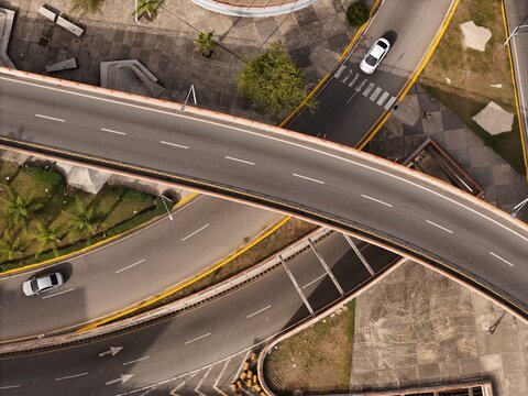 Aerial view of a highway interchange with cars driving on curved roads, surrounded by paved areas and palm trees in Santo Domingo, Distrito Nacional, Dominican Republic.